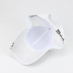 Détail d'une casquette blanche avec anneaux métalliques et broderie sur la sangle