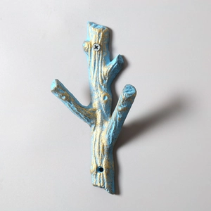 Detail of branch shaped cast iron wall hook with rustic blue and gold finish texture