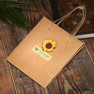 Detail of kraft paper gift bag with sunflower applique and braided gold handles