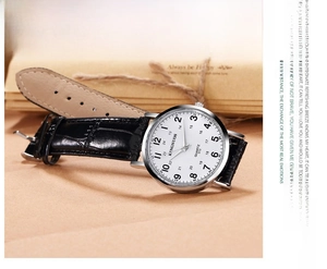 Macro detail of minimalist silver watch with black faux-leather strap and white dial