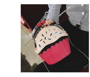 Person wearing a creative cupcake-shaped PU shoulder bag with pink rhinestones and chain strap