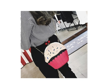 Detail of creative cupcake shoulder bag with pink base and cherry clasp worn by model