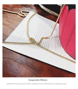 Close-up of golden snake chain strap and cross-grain texture on pink shoulder bag