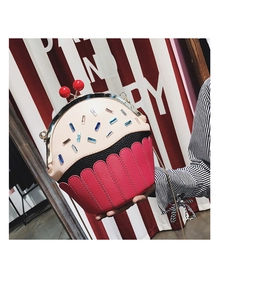 Close-up of creative cupcake-shaped shoulder bag with red cherry detail and rhinestones