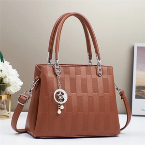 Close-up of brown handbag featuring geometric texture, silver hardware and pearl star charm