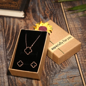 Rose gold four-leaf clover necklace and earrings set in a kraft paper gift box