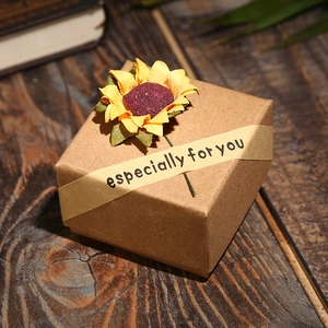 Close-up of brown kraft paper gift box with a yellow sunflower and vintage paper tape