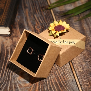 Detail of kraft paper jewelry box set with sunflower and clover earrings on wood