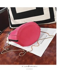 Detail view of round rose red PU leather bucket bag bottom with gold chain strap