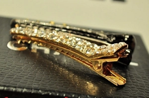 Macro detail of elegant gold hair clip with sparkling rhinestones on textured surface