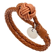 Detail van een bruine gevlochten leren armband met knoopsluiting en metalen bedeltje