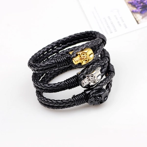 Three braided leather bracelets with skull charms in gold silver and black alloy