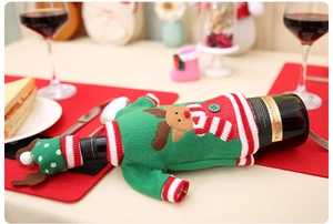 Detail of green knitted Christmas wine bottle cover with reindeer embroidery and mini hat