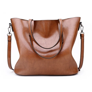 Detail of vintage brown tote bag showing smooth leather texture and metal strap buckles