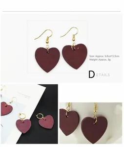 Detalle de pendientes de corazón de madera roja con ganchos dorados y textura de madera