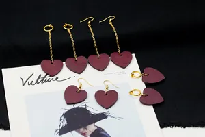 Detalle de pendientes de corazón de madera roja con cadenas doradas sobre revista de moda