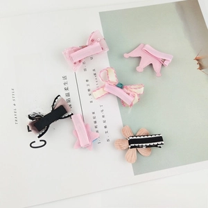 Detail view showing five pieces of mink fur crown clips and pink bow hairpins on a magazine