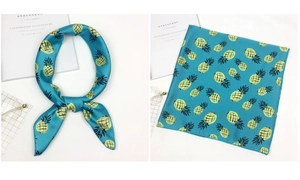 Detail of blue square silk scarf with yellow pineapple patterns tied as a stylish bow