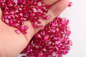 Macro shot of high-quality oval cut rose red synthetic rubies held in hand for jewelry making