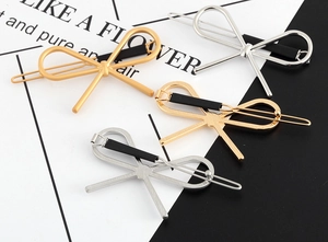Detailed view of four metal bow hair clips in gold and silver finishes on split background