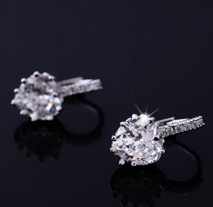 Macro shot of silver heart-shaped zircon earrings with claw setting and accent stones