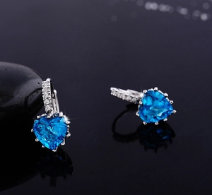 Macro shot of silver heart earrings with blue crystal stones and zircon inlay
