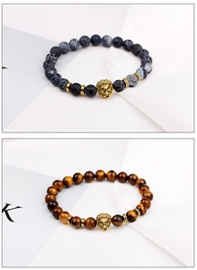 Detailed close-up of golden lion head beads on tiger eye and lava stone bracelets