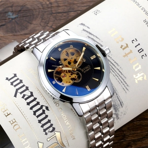 Silver automatic mechanical watch with blue skeleton dial placed on vintage bottle