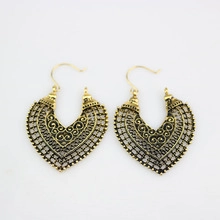Detailed macro view of vintage gold hollow heart earrings with ethnic metal patterns