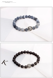 Close-up of lava rock and blue stone bracelets with silver lion head charms