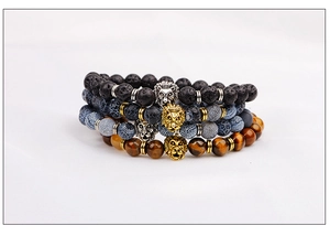 Detail of beaded men's bracelets featuring lava stone, tiger eye, and gold lion charms