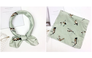 Detail of light green satin scarf with crane pattern and white stripes on white desk