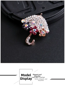 Dettaglio macro di una spilla a ombrello con strass, fiori di cristallo e placcatura oro rosa