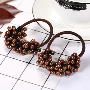 Detailed close-up of brown pearl beaded hair ties on a ceramic tile background