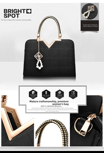 Detail of cross-pattern black handbag with golden V-decor and woven braid handle