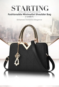 Detail of black geometric embossed handbag with gold V hardware and pearl pendant