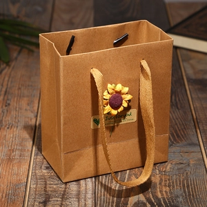 Brown kraft paper gift bag with sunflower and Just for you sticker on wood background