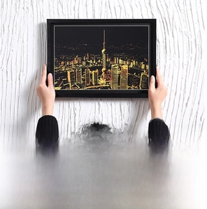 Detail of black scratch art frame showing vertical wall mounting on a white textured wall