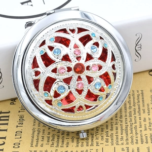 Detailed view of hollow floral pattern on a silver vintage makeup mirror with colorful crystals