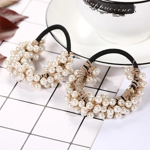 Detail of handmade black elastic hair ties with white pearls and gold wire accents