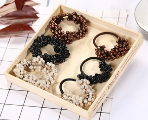 Detailed set of handmade woven elastic hair ties with pearls and crystal beads in a tray