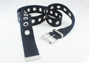 Detail of black canvas belt featuring dense silver metal eyelets and a square pin buckle