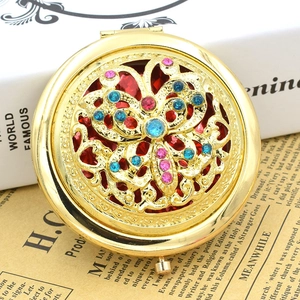 Macro view of golden hollow butterfly pattern with pink and blue rhinestones on makeup mirror