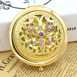 Detailed view of vintage gold makeup mirror with hollow floral design and colorful rhinestones