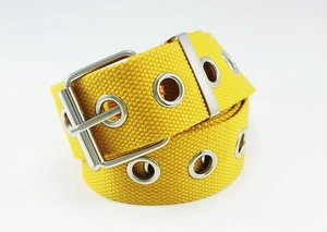 Detailed view of yellow canvas belt featuring multiple silver metal eyelets and square buckle