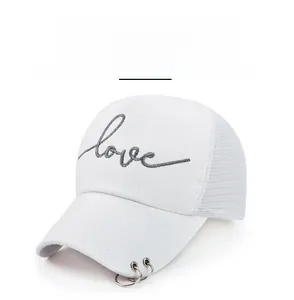 Vue détaillée de la casquette blanche avec anneaux argentés sur la visière et broderie