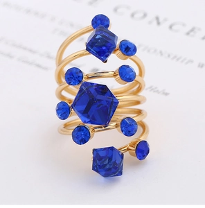 Macro detail of gold-plated spiral ring with blue geometric crystals on white surface
