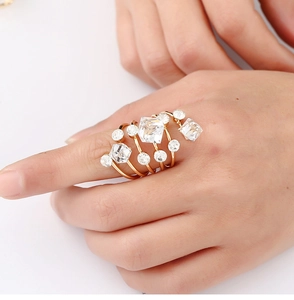 Detailed view of a multi-layer golden spiral ring set with clear crystals on a hand