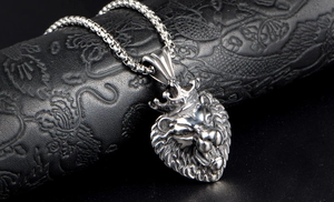 Macro view of silver lion head pendant with crown on textured black background