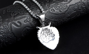 Macro detail of a silver lion head pendant on a box pearl chain over black leather background
